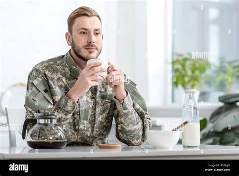 Handsome Man In Military Uniform Drinking Coffee At Kitchen Table Stock