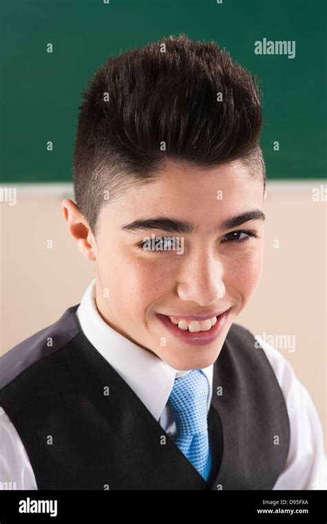 Head And Shoulders Portrait Of Boy In Front Of Chalkboard In Classroom