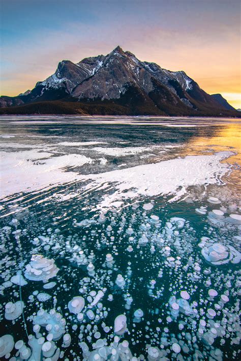 Ice Floes Floating On The Water In Front Of A Mountain Range At Sunset