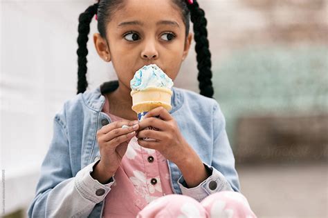 Young Girl Looks To Side While Eating An Ice Cream Cone By Stocksy