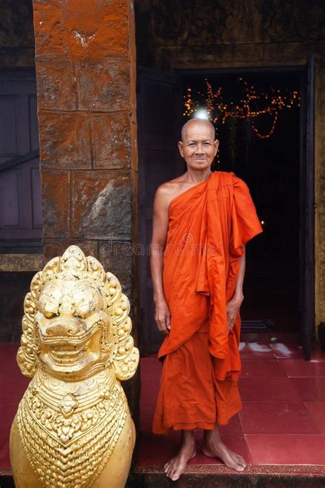Khmer Monk Standing Near A Singha Khmer Statue At The Ancient Temple