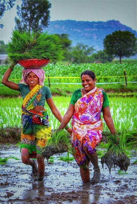 Two Women Carrying Plants On Their Heads In The Mud With Mountains In