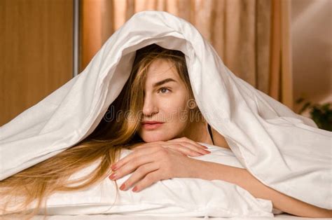 Beautiful Young Woman In Morning In White Bed In Rays Of Sun Covered With Blanket With Her Head