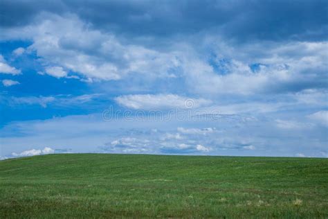Cloudy Sky Over A Green Pasture With A Slight Slope With Copy Space