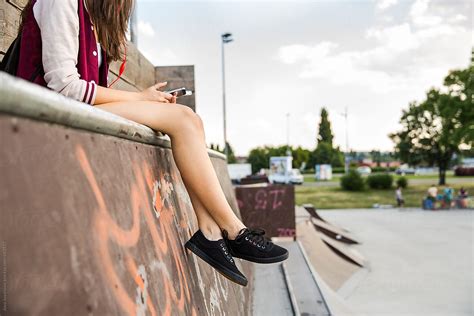 woman checking her phone sitting in a skate park by stocksy contributor jovo jovanovic stocksy