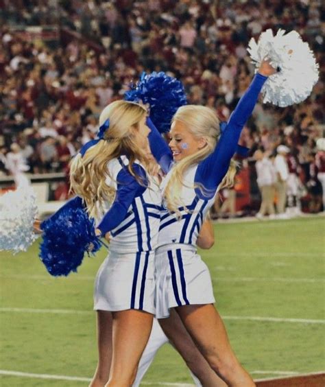 Two Cheerleaders In Blue And White Uniforms On The Field