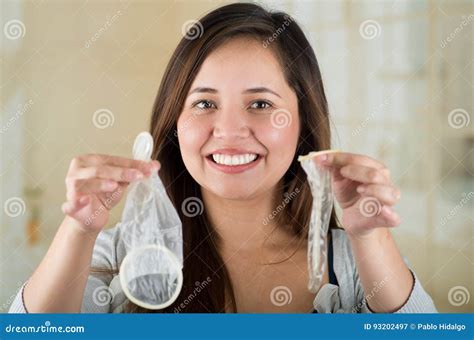 surprised girl holding an open female condom in one hand and an open male condon in her other