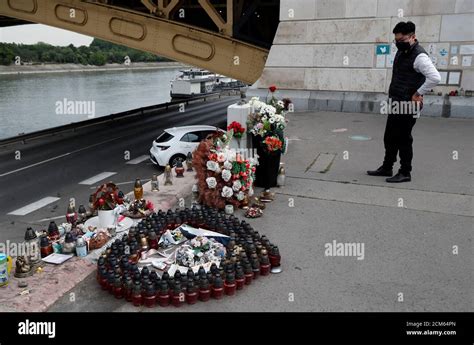 A Mourner Wearing A Face Mask Looks At Flowers And Candles Placed Near