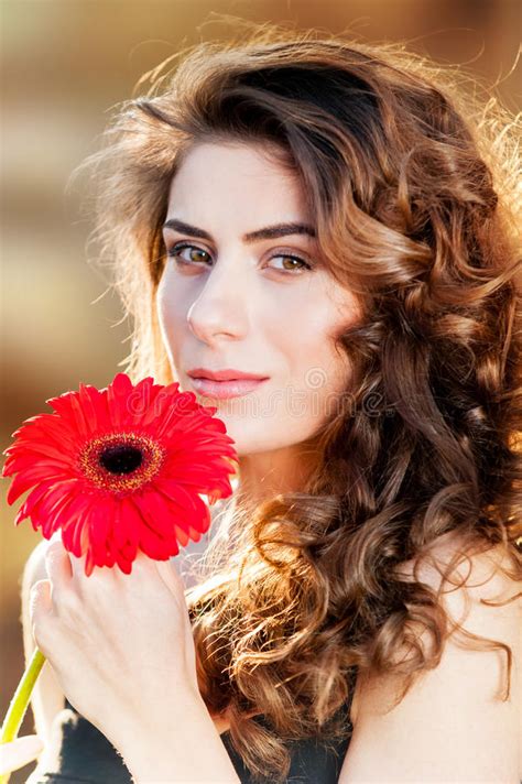 Portrait Of Young Beautiful Woman Holding A Red Flower Stock Image