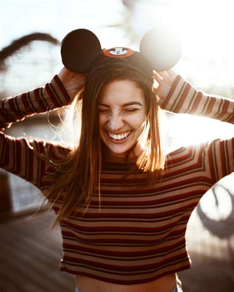 A Woman Wearing Mickey Mouse Ears Smiling And Holding Her Hair In Front