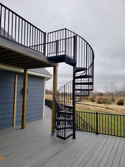 Winding modern staircase with glass railing from upper landing in 2 story foyer in a modern home. Spiral Stairs on Two level deck in 2020 | Deck builders, Building a deck, Deck stairs