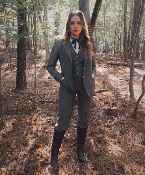 A Woman Standing In The Woods With Her Hands On Her Hips Wearing A Suit