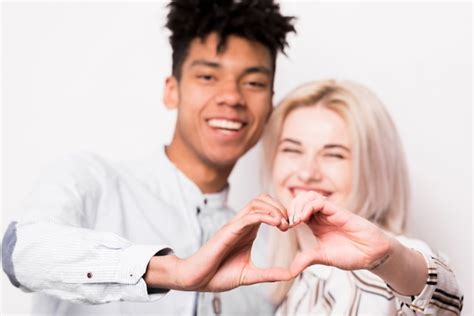 El retrato de los pares interraciales sonrientes que hacen el corazón forma con sus manos Foto
