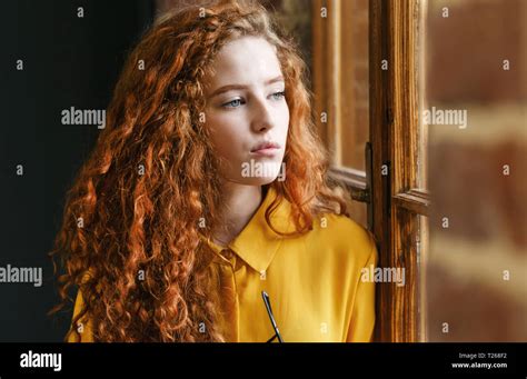 Portrait Of Curly Redhead Girl In The Yellow Shirt Looking To The