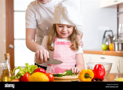 Mother And Daughter Cooking And Cutting Vegetables On Kitchen Stock