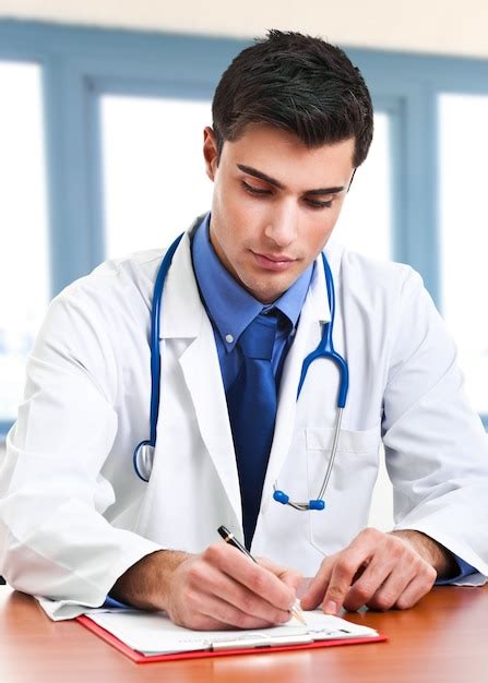 Premium Photo Smiling Young Handsome Doctor Writing A Prescription