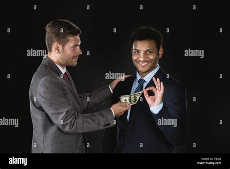 Businessman Giving Money And Bribing Business Partner Isolated On Black