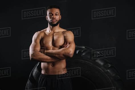 muscular shirtless african american sportsman standing with crossed arms near big tire and