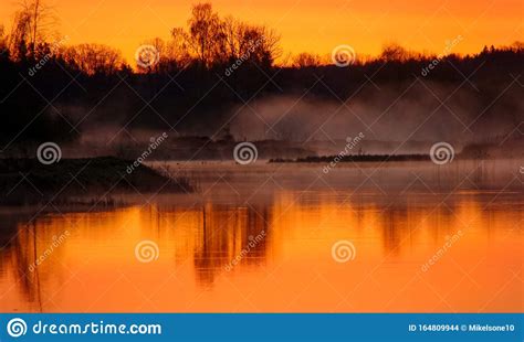 Sunrise Landscape At The Water Trees Reflection In The Lake On Foggy