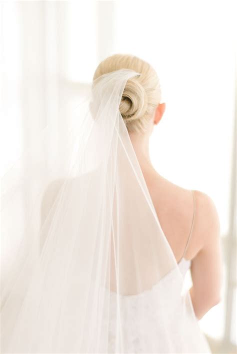 A Woman In A Wedding Dress With A Veil On Her Head Looking Out The Window