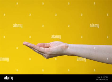 Female Hand Keeping Empty Cupped Palm Isolated On Yellow Background