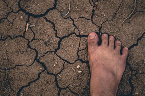 Foot On Dried Cracked Earth Soil Ground Texture Background Stock Photo