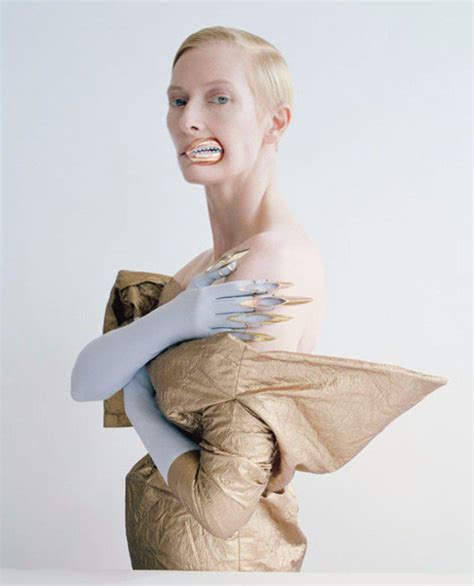 A Woman In A Gold Dress With Her Arms Wrapped Around Her Body And Hands On Her Chest