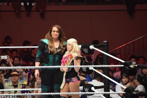Two Women Standing Next To Each Other In A Wrestling Ring