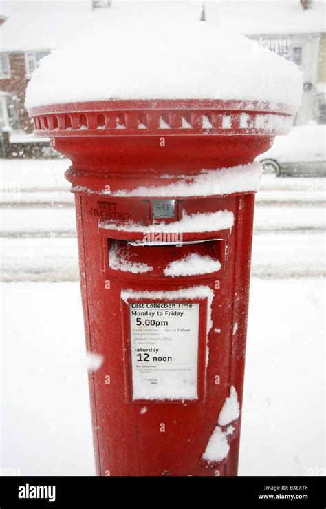 A Red British Post Box Overflowing With Mail Covered In Snow Stock