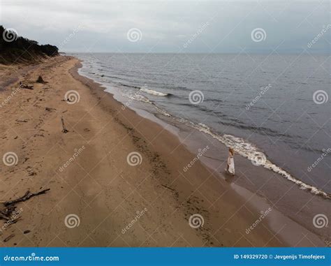 Aerial Beautiful Young Blonde Woman Beach Nymph In White Dress Near Sea With Waves During A Dull
