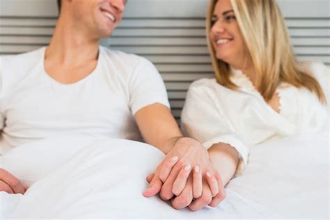 Free Photo Cheerful Man Holding Hand Of Young Woman In Bed