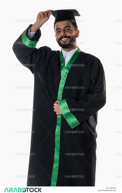 بورتريه لطالب عربي سعودي خليجي يرتدي العباءه وقبعة التخرج، يمسك قبعة التخرج ايماءات تدل على