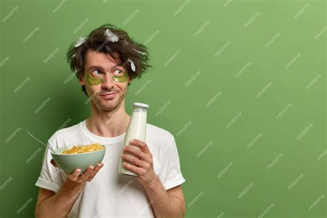 Free Photo Horizontal Shot Of Young Man Awakes In Morning Holds Bowl Of Cereals And Milk For