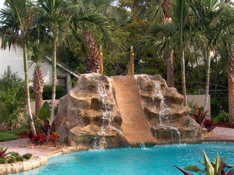 Swimming pool water features that incorporate natural looking stone give the illusion that one is swimming in a natural pond. Artificial Rock Waterfalls For Pools | Backyard Design Ideas