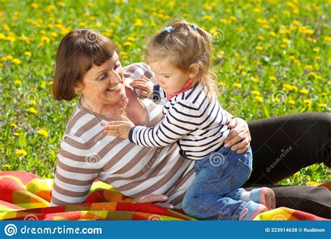 Grandmother And Little Granddaughter Playing On The Meadow Of Yellow