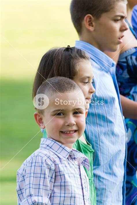 Young Children Standing In A Row With A Little Boy Smiling Towards The