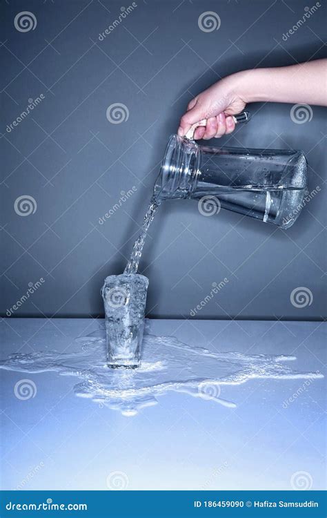 Human Hand Pouring Water Into An Overflowing Glass Stock Photo Image