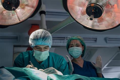 Team Of Professional Doctors Performing Operation In Surgery Room Stock