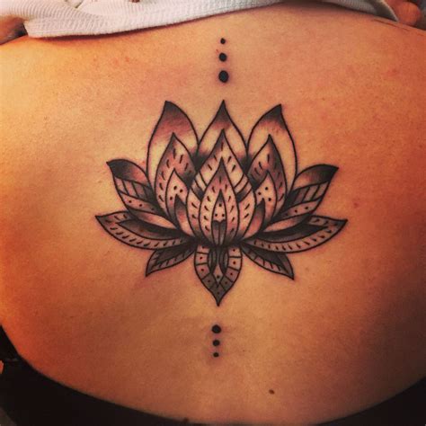 A Womans Lower Back Tattoo With A Lotus Flower On The Bottom And An