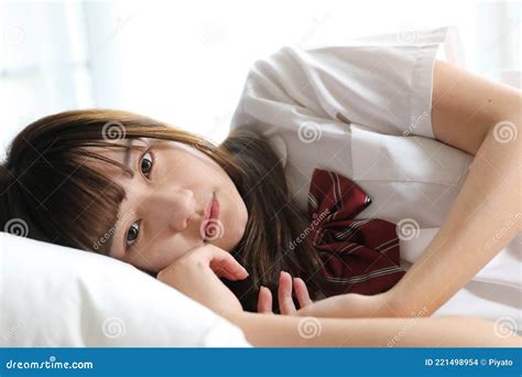 portrait japanese school girl uniform sleep and look at camera in white tone bed room stock