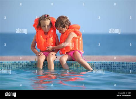 Zwei Kleine Mädchen In Schwimmwesten Sitzen Auf Sims Pool Resort