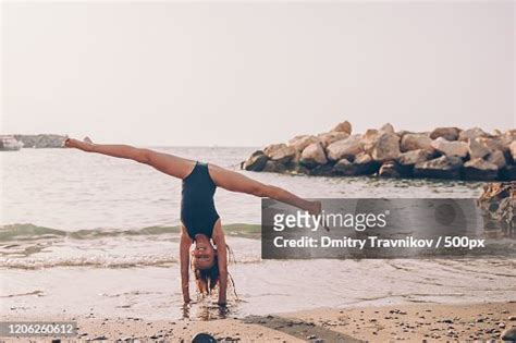 Young Female Gymnast Doing Splits Standing On Hands On Beach High Res