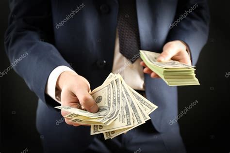 Businessman Giving Money On Dark Background — Stock Photo © Belchonock