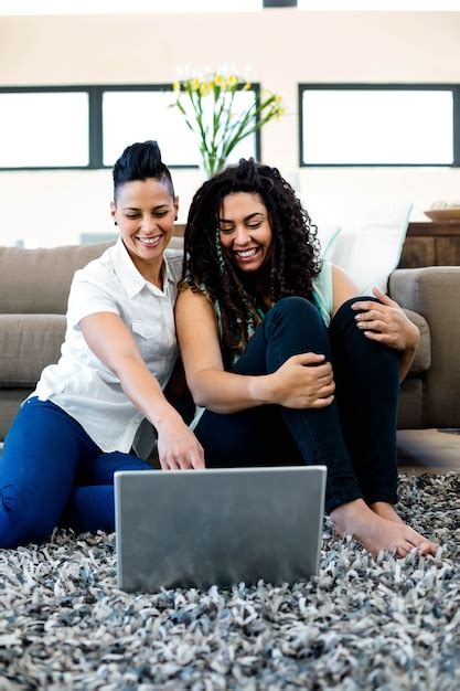 premium photo smiling lesbian couple sitting on rug and using laptop in living room