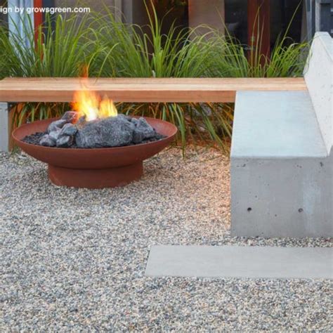 A Fire Pit Sitting In The Middle Of A Gravel Area Next To A Wooden Bench