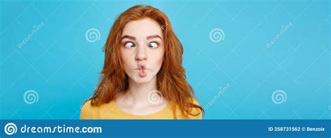 headshot portrait of happy ginger red hair girl with funny face looking at camera pastel blue