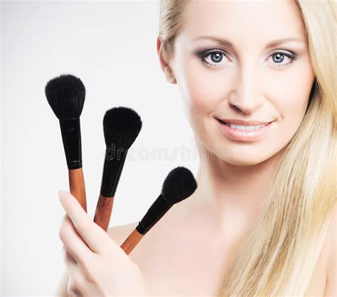 Portrait Of A Young Blond Woman Holding Makeup Brushes Stock Image