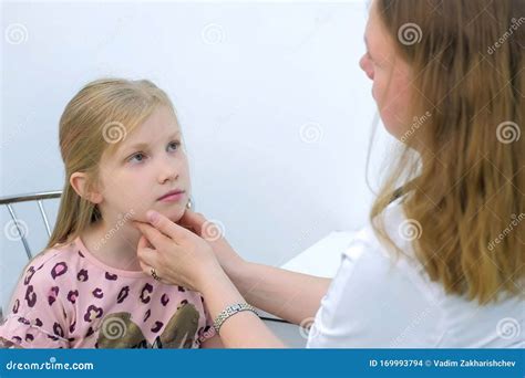 Pediatrician Woman Probing Lymph Nodes On Neck Of Girl Child During