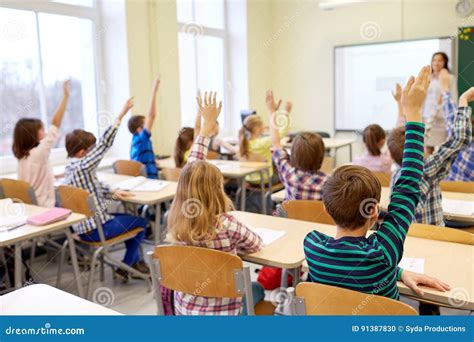 Group Of School Kids Raising Hands In Classroom Stock Photo Image Of