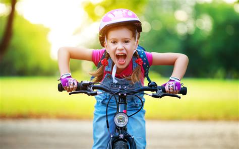 Happy Cheerful Child Girl Riding A Bike In Park In Nature Realities